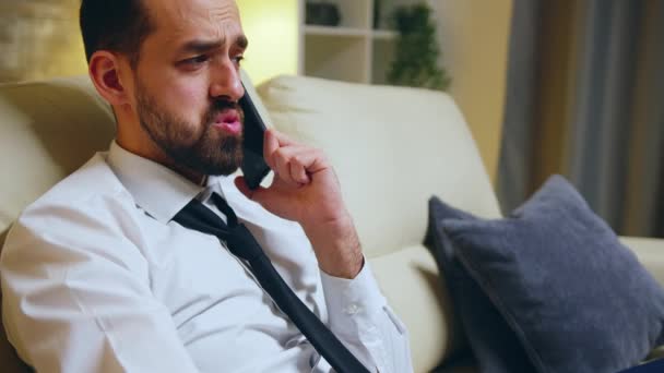 Successful businessman eating a burger sitting on couch after a tiring day — Αρχείο Βίντεο