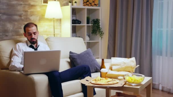 Jeune entrepreneur assis sur le canapé travaillant sur un ordinateur portable — Video