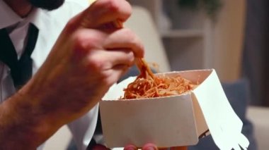 Close up of tired entrepreneur eating noodles