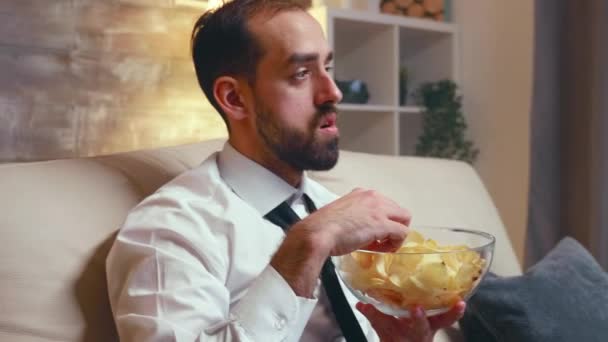 Empresário em uso formal comer batatas fritas de uma tigela — Vídeo de Stock