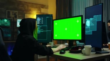 Hacker girl wearing a black hoodie in front of computer