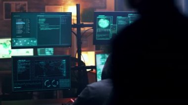 Back view of hooded cyber terrorist using super computer