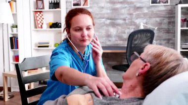 Female nurse listening senior woman heart