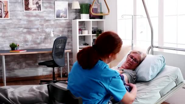 Female nurse checking blood pressure of old woman in nursing home — Stock Video