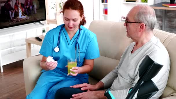 Врач в доме престарелых дает старику таблетки — стоковое видео