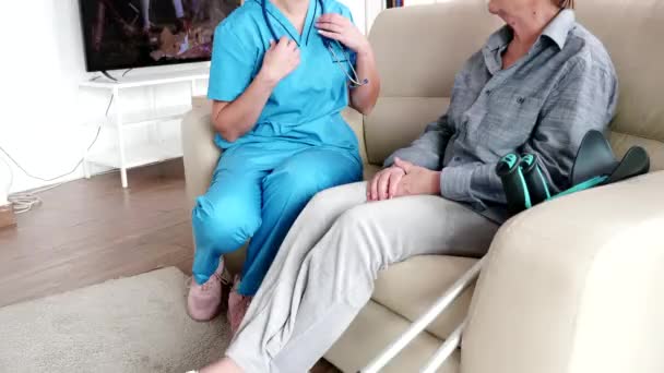 Женщина-медсестра в доме престарелых проверяет старушку — стоковое видео