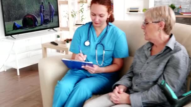Медсестра с рыжими волосами делает заметки на планшете — стоковое видео