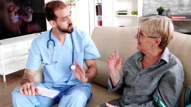 Male nurse talking with old lady patient in retirement home — Stockvideo