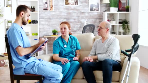 Team of male and female nurses talking with an old and retired man — Stockvideo