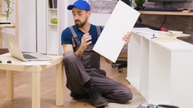 Professional worker assemble a shelf consults instructions