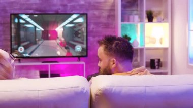 Best friends relaxing on couch and playing online video games