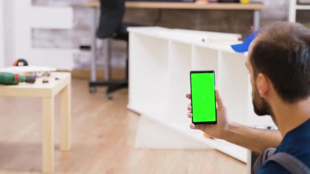 Vista trasera del trabajador masculino sosteniendo el teléfono con pantalla verde — Vídeos de Stock