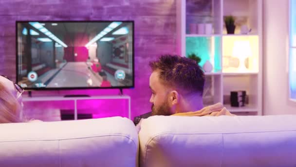 Mejores amigos relajándose en el sofá y jugando videojuegos en línea — Vídeos de Stock