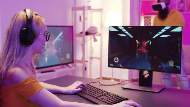 Flicka spelar shooter spel i ett rum med färgglada neon lampor — Stockvideo