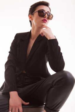 Stüdyoda beyaz arka planda poz veren güneş gözlüklü güzel bir model.