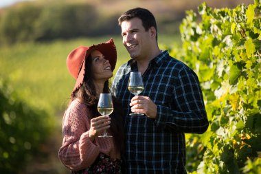 Güzel, genç bir kadın elinde bir kadeh şarapla kocasına bakıyor.