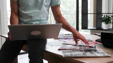 Close up with the hands and feet of a young designer working on a laptop