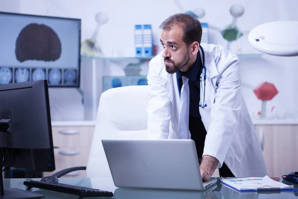 Retrato del médico trabajando en el portátil y mirando por encima de su monitor —  Fotos de Stock