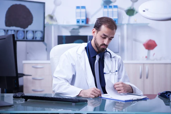 Молодой и умный врач проверяет список своих пациентов в блокноте — стоковое фото