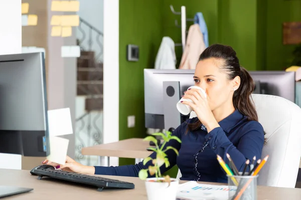 Молодая девушка пьет кофе в офисе — стоковое фото