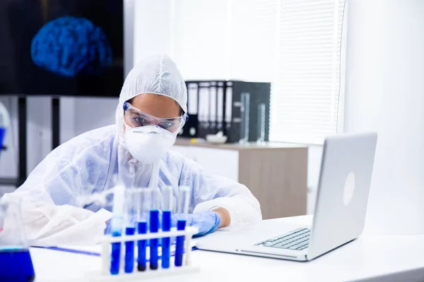 Forskaren tittar på en tubhållare med en blå vätska i — Stockfoto