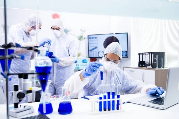 Equipo joven de químicos examina una sustancia azul que está en el tubo — Foto de Stock