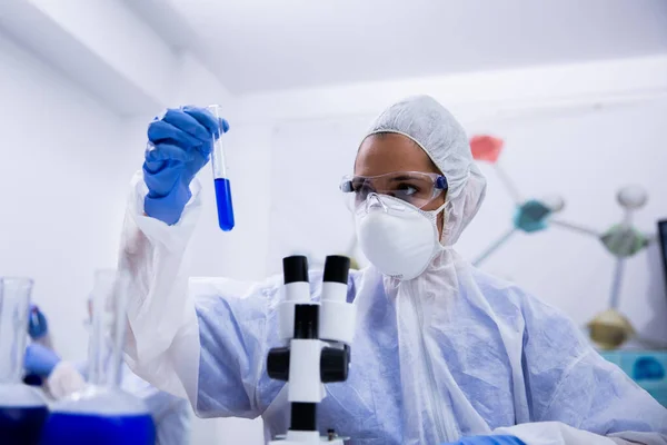 Ученый в современной исследовательской лаборатории держит пробирку с голубым раствором — стоковое фото