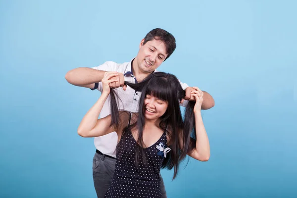 Caucasiano jovem provocando sua namorada asiática puxando seu cabelo — Fotografia de Stock