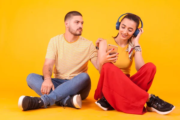 Sorrindo namorada com fone de ouvido ignorando seu namorado — Fotografia de Stock