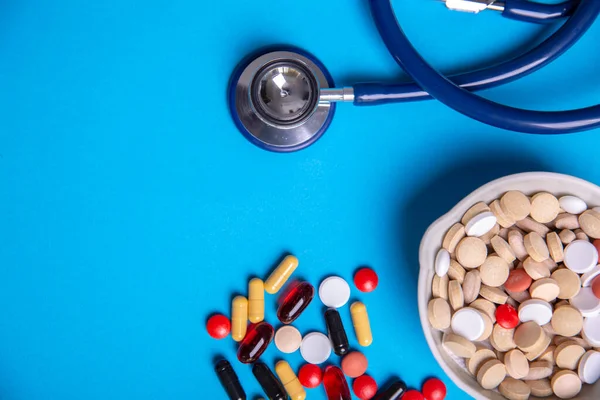 Bovenaanzicht met een stethoscoop en pillen van vele kleuren en een kom pillen — Stockfoto