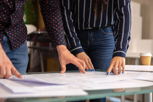 Cierre con las manos de dos arquitectos que colocan unas sábanas sobre la mesa —  Fotos de Stock