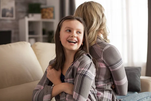 Niña con una gran sonrisa y frenos sentados espalda con espalda — Foto de Stock