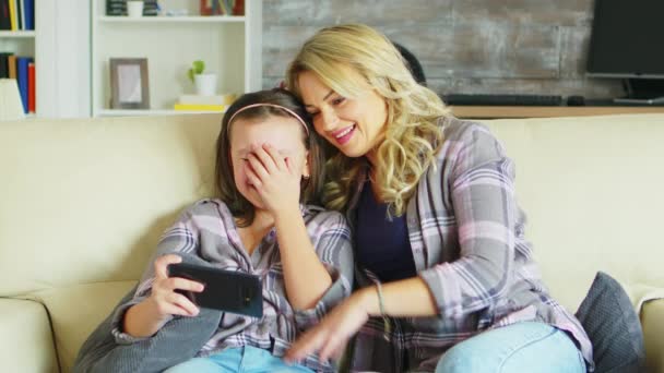 Ung mor och hennes dotter kopplar av på soffan — Stockvideo