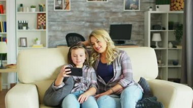 Küçük kız akıllı telefondan video izlerken gülüyor.