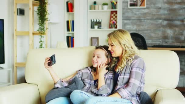 Menina e sua mãe sentados no sofá na sala de estar — Vídeo de Stock