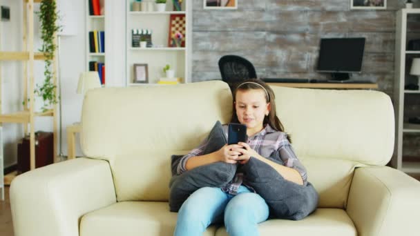 Fröhliches kleines Mädchen mit Zahnspange sitzt auf der Couch — Stockvideo