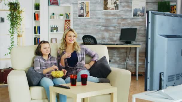 Menina comendo batatas fritas enquanto assiste tv com sua mãe — Vídeo de Stock