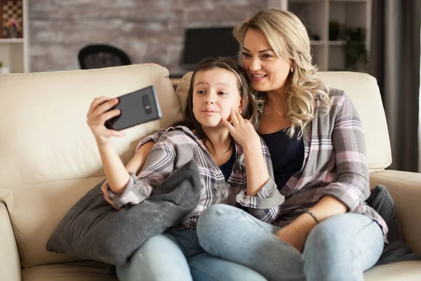 Little girl making funny faces during a video call — Stock Photo, Image