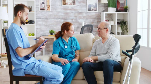 Team of male and female nurses talking with an old and retired man — ストック写真