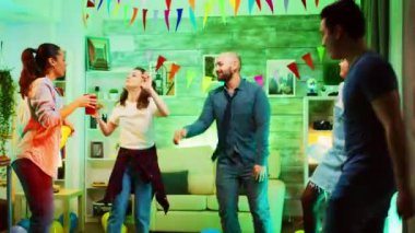 Partide arkadaşlarıyla birlikte süper kahraman kırmızı pelerin giyen heyecanlı genç adam.