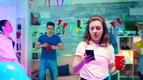 Ragazza annoiata che scrive sul suo smartphone alla festa dei suoi amici — Video Stock