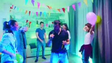 Genç adam bir partide bira şişesi tutuyor.