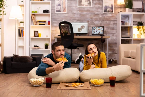 Casal sentado no chão e assistindo TV em sua sala de estar — Fotografia de Stock