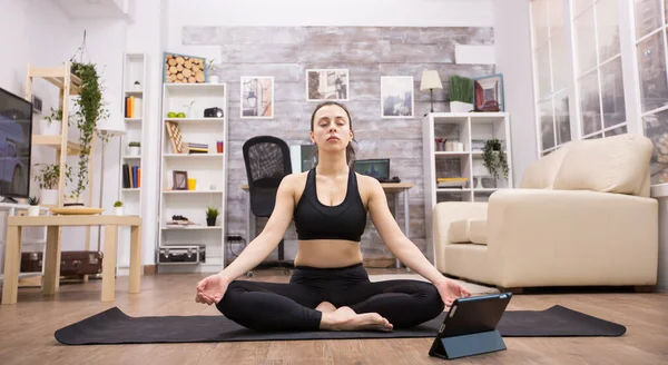 Tabletcomputer voor jonge vrouw die yoga doet — Stockfoto