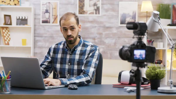 Famoso giovane vlogger digitando sul computer portatile mentre parla — Foto Stock