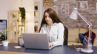 Evden çalışırken dizüstü bilgisayarda yazan kız