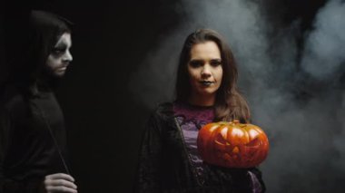 Karanlık ölüm meleğinin yanında cadı gibi giyinmiş genç bir kadın.