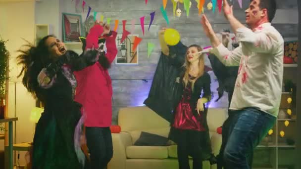 Opgewonden groep mensen verkleed voor Halloween in verschillende personages dansen en plezier hebben op huisfeest — Stockvideo