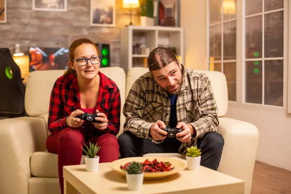 Пара геймерів грає в відеоігри по телевізору з бездротовими контролерами в руках — стокове фото