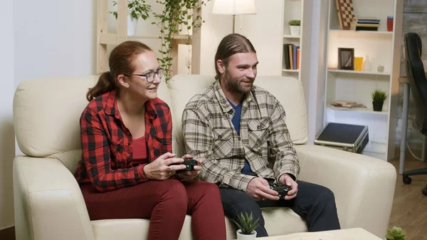 Husband and wife sitting on sofa playing video games — Stock Photo, Image